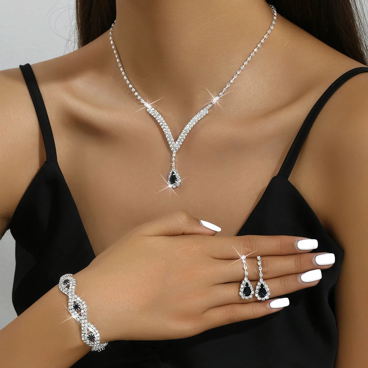 Luxury Silver Jewelry Set with Black Stones A sophisticated set comprising a necklace, earrings, and bracelet, all adorned with teardrop-shaped black stones and sparkling crystal accents. Perfect for special occasions.