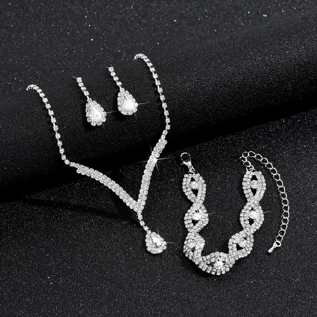 Luxury Silver Jewelry Set with Black Stones A sophisticated set comprising a necklace, earrings, and bracelet, all adorned with teardrop-shaped black stones and sparkling crystal accents. Perfect for special occasions.