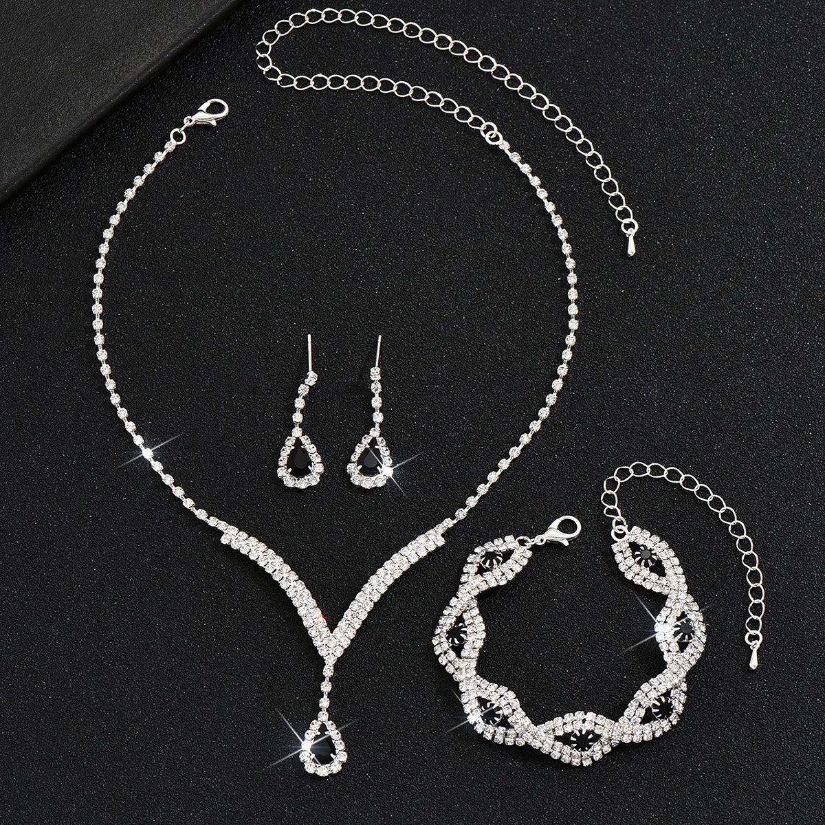 Luxury Silver Jewelry Set with Black Stones A sophisticated set comprising a necklace, earrings, and bracelet, all adorned with teardrop-shaped black stones and sparkling crystal accents. Perfect for special occasions.